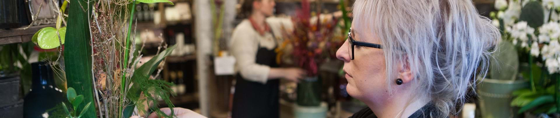 Dorthe står i butikken og retter på nogle grønne planter